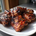 Close-up of juicy grilled chicken thighs coated in an Easy Balsamic Chicken Marinade, sprinkled with herbs.