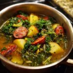 Close-up of a pot filled with Easy Caldo Verde Soup, featuring kale, potatoes, and sliced chorizo sausage.