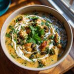 A bowl of Easy Creamy Chicken Poblano Soup with Black Beans, garnished with cilantro and a swirl of cream.