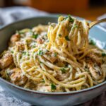Close-up of a fork twirling creamy Easy Garlic Parmesan Chicken Pasta, garnished with parsley and Parmesan cheese.