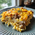 A close-up of a slice of Hearty Southern Five Layer Beef Casserole, featuring layers of pasta, seasoned ground beef, and melted cheddar cheese.