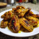 A plate of golden brown, crispy Lemon Pepper Air Fryer Wings, garnished with fresh lemon zest.