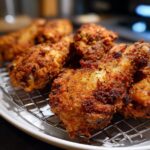Close-up of golden brown, crispy Parmesan-Crusted Air Fryer Tenders on a cooling rack.