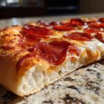 A close-up shot of a delicious slice of Pepperoni Air Fryer Pizza, showcasing the crispy crust, melted cheese, and savory pepperoni.