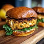 Close-up of a perfectly cooked Salmon Burger on a toasted bun with fresh arugula.