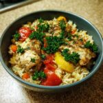 A close-up of a bowl filled with Slow Cooker Lemon Herb Chicken and Rice, garnished with fresh parsley.