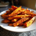 A pile of delicious Sweet Potato Air Fryer Fries seasoned with spices on a white plate.