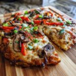 A close-up of a delicious Veggie Air Fryer Pizza slice, topped with melted cheese, mushrooms, red peppers, and green onions.