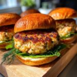 Close-up of delicious air fryer salmon burgers on toasted buns with fresh lettuce and dill.