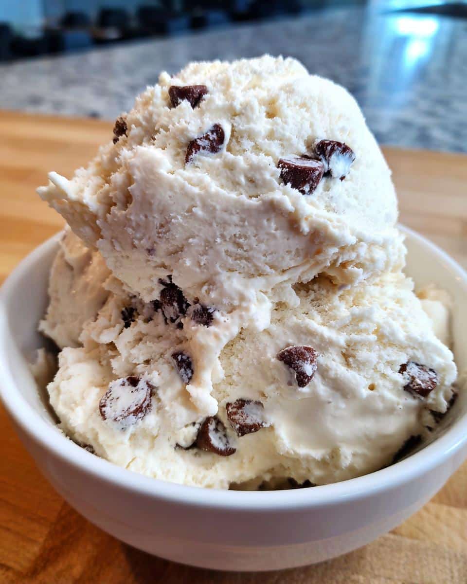 Close-up of creamy cottage cheese ice cream with dark chocolate chips in a white bowl.