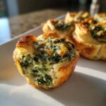A close-up of a crescent roll spinach dip bite, showing the flaky pastry and creamy spinach filling.