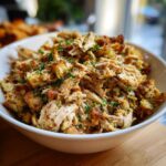 A white bowl filled with delicious make ahead crockpot chicken stuffing, garnished with fresh parsley.