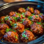 Close-up of glazed meatballs in a slow cooker, garnished with fresh parsley, perfect for meatball potluck ideas.