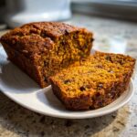 A slice of moist pumpkin bread with chocolate chips, showcasing its rich texture and dark chocolate chunks.