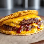 Close-up of a delicious Smashburger Taco with two beef patties, melted cheddar cheese, and a drizzle of sauce.