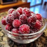 Close-up of sparkling candied cranberries in a glass bowl, ready for holiday decoration.