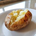 Close-up of a fluffy 6-minute “baked” potato on a white plate, ready to be enjoyed.