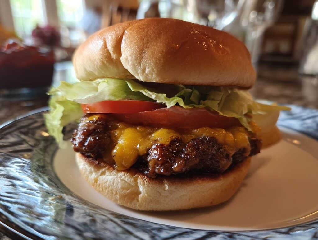A delicious Air Fryer Burger with cheese, tomato, and lettuce on a bun, sitting on a plate.