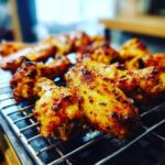 Close-up of golden brown Air Fryer Chicken Wings on a wire rack, seasoned with herbs and spices.