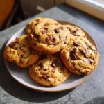 A plate of freshly baked air-fryer chocolate chip cookies, golden brown and loaded with chocolate chunks.