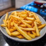 A plate piled high with golden, crispy Air Fryer French Fries, ready to eat.