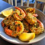 A plate of golden Air Fryer Shrimp garnished with herbs and served with lemon wedges.