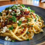 A plate of Caramelized onion feta pasta, garnished with fresh parsley, ready to be enjoyed.