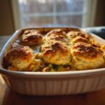 Close-up of a freshly baked Chicken cobbler in a white baking dish with golden brown biscuits on top.