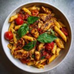 Overhead shot of a bowl of Chicken Tomato Basil Pasta with penne, juicy tomatoes, grilled chicken, and fresh basil.