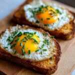 Two pieces of cloud eggs (cloud toast) on a wooden board, garnished with chives. Yummy breakfast.