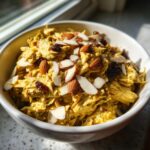 A bowl of Coronation chicken salad with almonds and raisins, ready to be served.