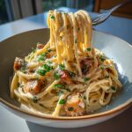 A fork lifts a swirl of creamy smoked sausage pasta, garnished with fresh parsley and grated cheese.