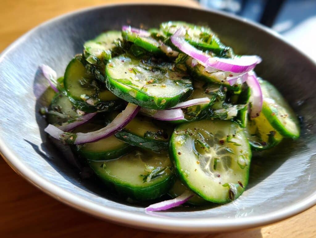 Close-up of a fresh cucumber salad in a bowl, featuring sliced cucumbers and red onion.