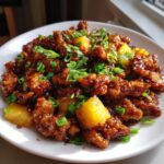 A plate of delicious dump and go crockpot pineapple chicken, garnished with green onions.
