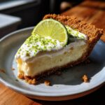 A delicious slice of Gluten-Free Key Lime Pie topped with whipped cream, lime zest, and a lime wedge.