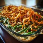 A close-up of a freshly baked green bean casserole topped with golden crispy fried onions.