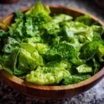 A wooden bowl filled with fresh green goddess salad, featuring crisp lettuce and a creamy dressing.