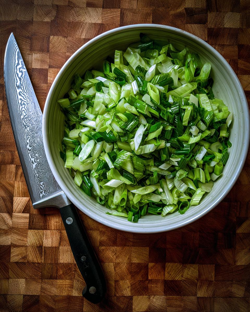 Diced green onions in a bowl with a knife, ready for a Green goddess salad recipe.