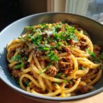 A close-up of a bowl of High Protein Creamy Beef Pasta, topped with fresh parsley and grated cheese.