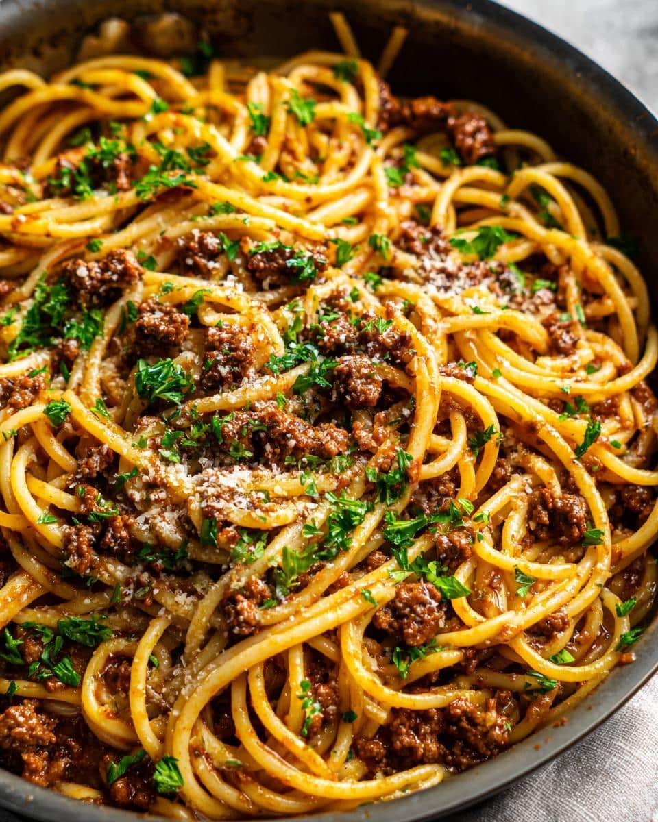 Close-up of a pan filled with High Protein Creamy Beef Pasta, garnished with parsley and parmesan.