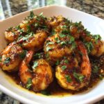 A close-up of a bowl filled with glistening High-Protein Honey Garlic Shrimp, garnished with fresh parsley.