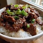 A flavorful hot honey beef bowl with rice, sesame seeds, and green onions.