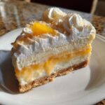 A delicious slice of Orange Cream Tart with whipped cream and orange garnish on a white plate.