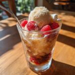 A creative soda float with ice cream, raspberries, and soda in a glass.