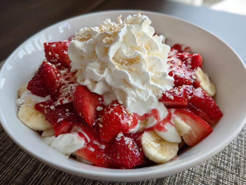A delicious Strawberry Banana Split dessert in a bowl, topped with whipped cream, strawberries, and bananas.