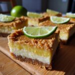 Close-up of Vegan Lime Bars topped with fresh lime slices on a wooden board.