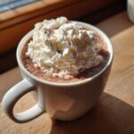 A mug of decadent french hot chocolate topped with a generous swirl of whipped cream and chocolate shavings.