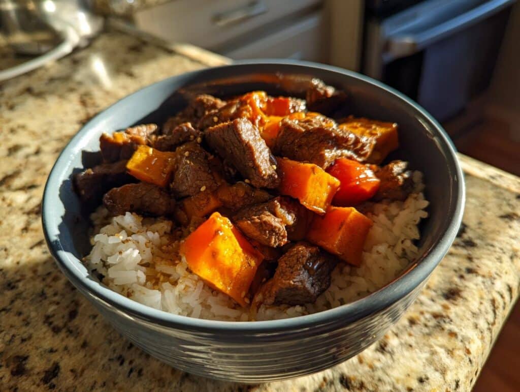 A delicious Hot Honey Sweet Potato Beef Bowl with rice, beef, and sweet potatoes in a gray bowl.