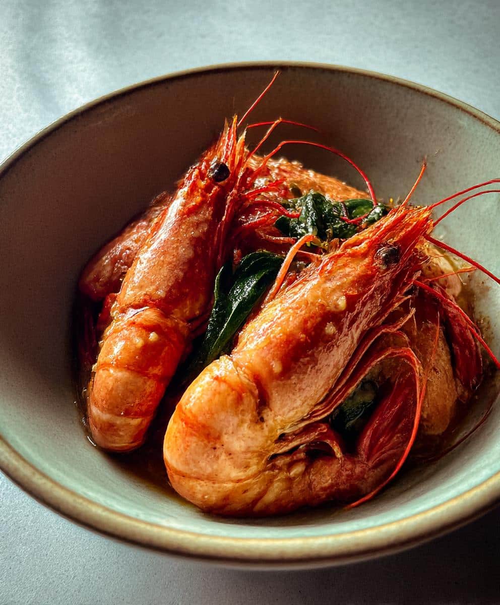 Close-up of langostino lobster recipes in a bowl, garnished with herbs and sauce.