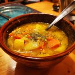 A bowl of hearty winter soup recipes with carrots, potatoes, and herbs, ready to warm you up.